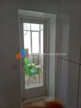 Pogled kroz staklena vrata na zastakljenu terasu sa garniturom za sedenje. - image 9