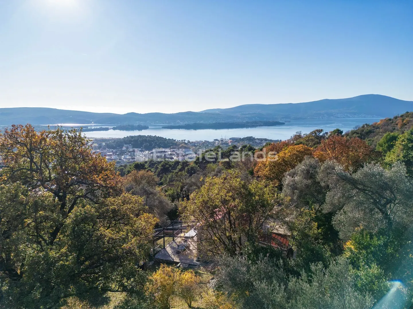 Pogled iz vazduha na prirodu i okolinu sa kućom okruženom zelenilom.