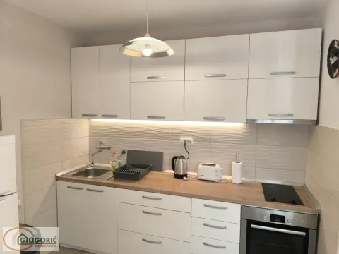 Small kitchen with white units, built-in oven and sink. - image 5