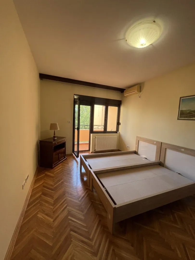 Bright bedroom with parquet flooring and balcony access.