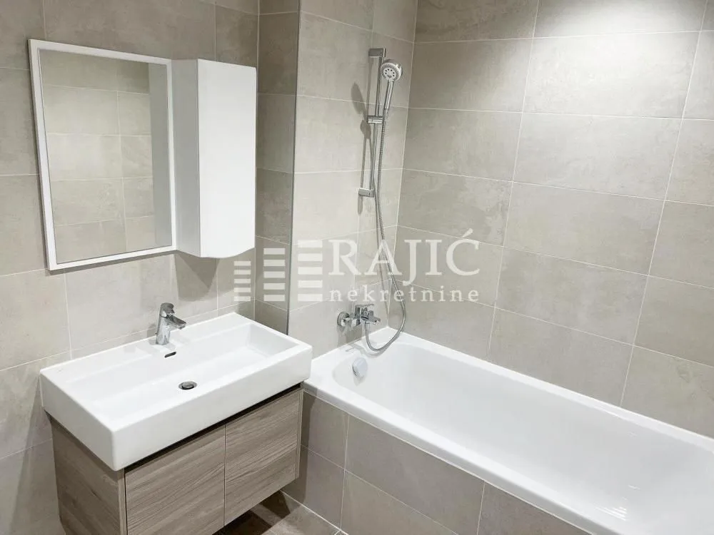Modernly equipped bathroom with a bathtub, sink, and mirror.