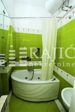 Manje kupatilo sa ugaonom kadom i zelenim pločicama. - image 10