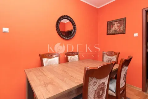 Trpezarija sa drvenim stolom i stolicama pored narandžastog zida. - image 4