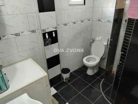 Manje kupatilo sa tuš kabinom, wc šoljom i pločicama u crno-beloj kombinaciji. - image 5
