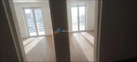 View from the hallway into two empty rooms with wooden flooring and balcony doors. - image 2