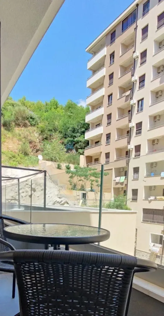 Pogled sa terase na susjednu zgradu i zeleno brdo.