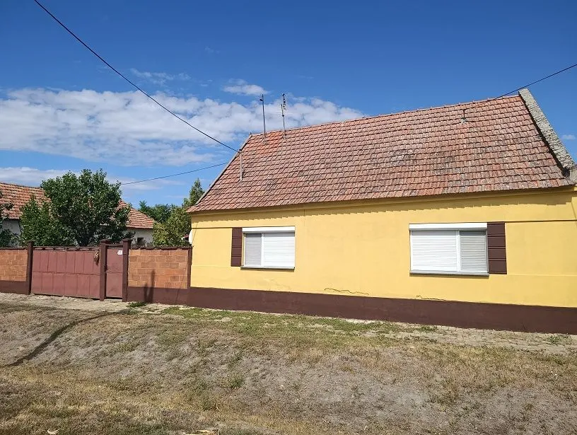Pogled na prednju fasadu kuće sa dvorištem.