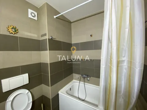 Bathroom equipped with a bathtub, toilet, and brown-toned tiles. - image 4