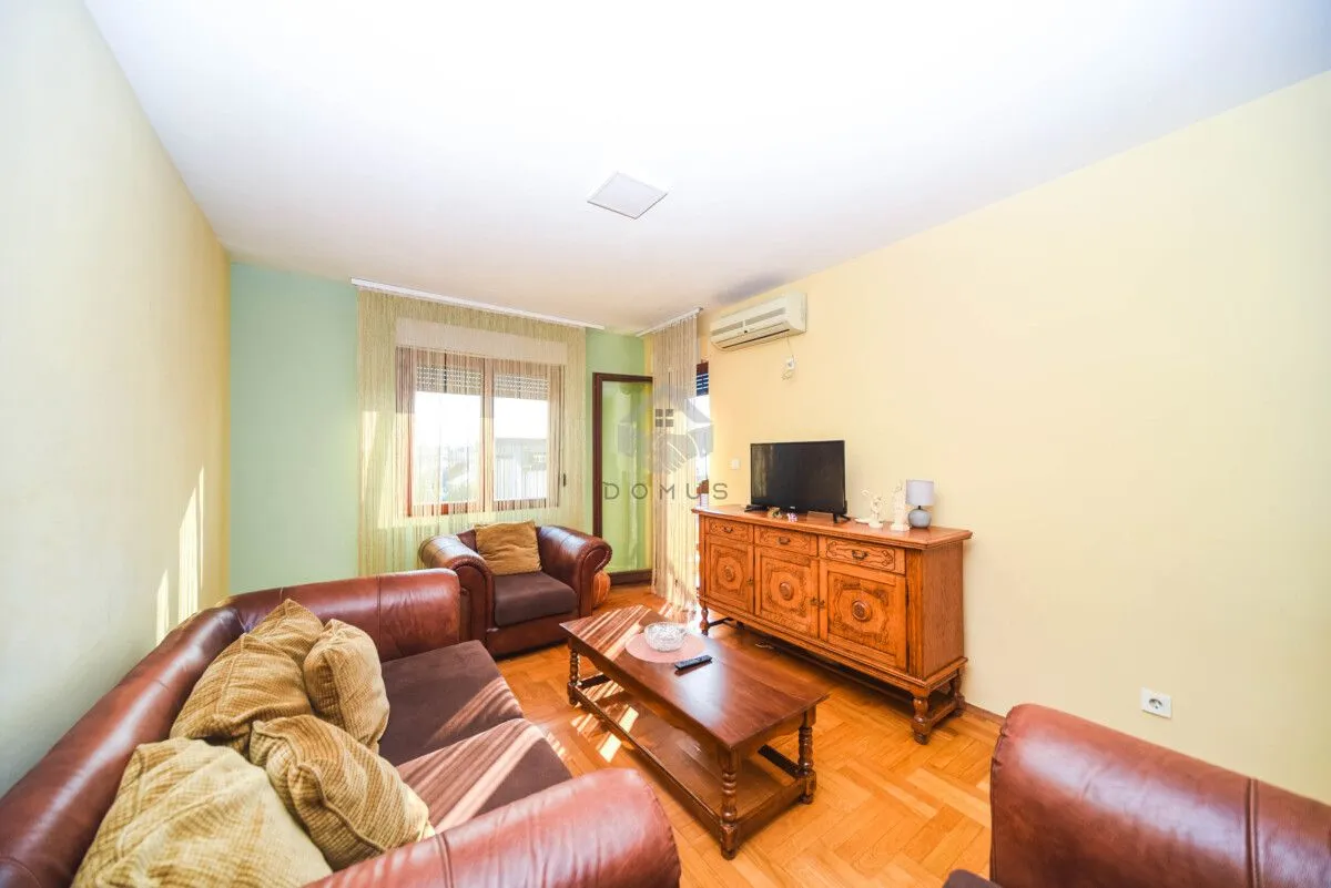 Living room with leather sofas, a wooden coffee table, and a TV cabinet.