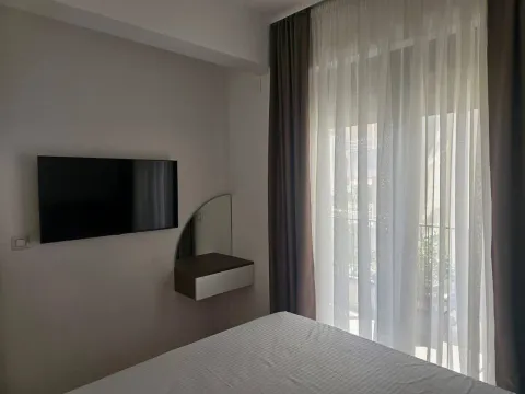 Namještena spavaća soba sa krevetom, televizorom na zidu i izlazom na terasu. - image 6