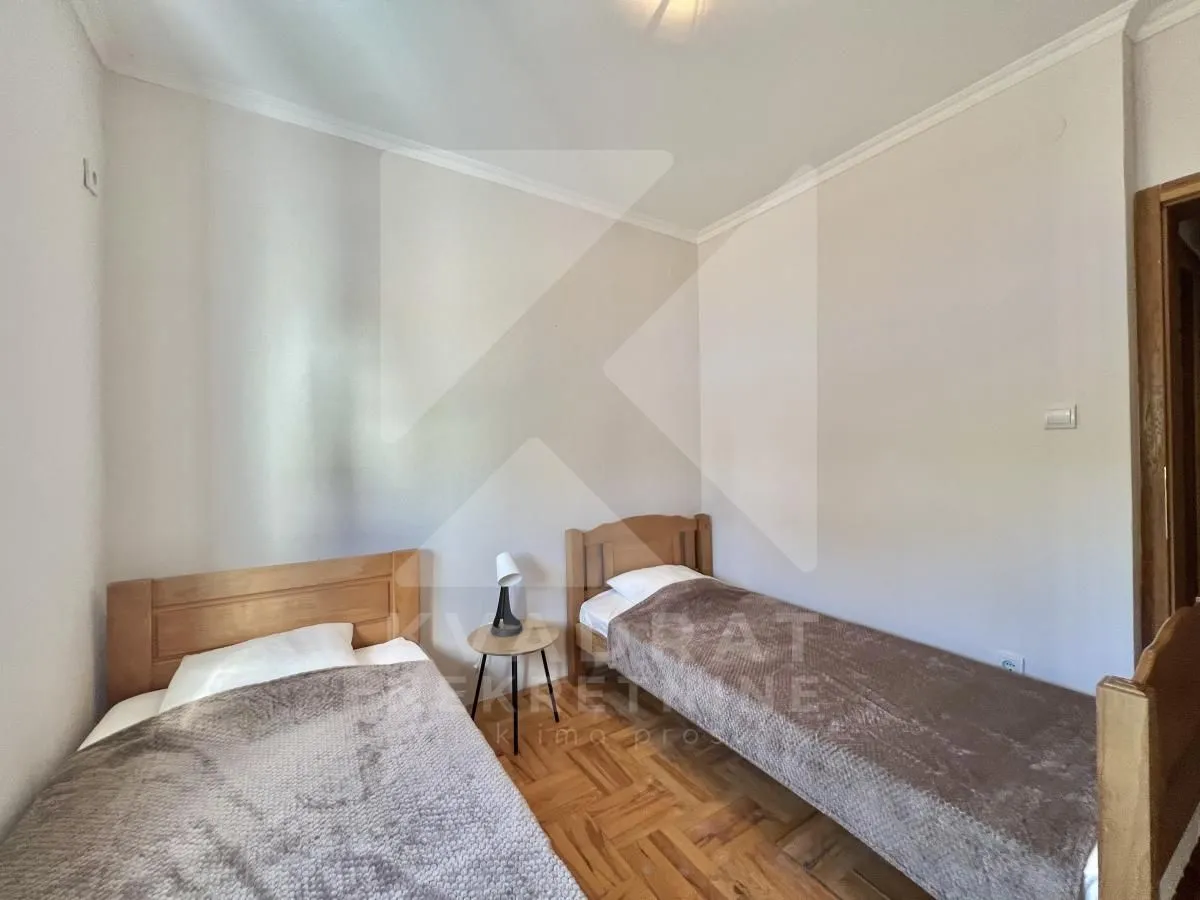 Bedroom with two wooden beds and a bedside table.
