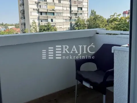 Small balcony with a chair and a view of surrounding buildings. - image 10