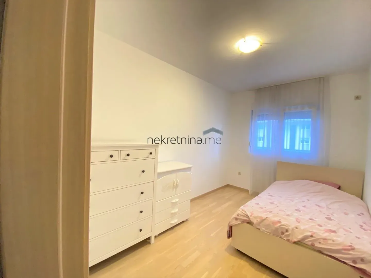 Bright and tidy bedroom with a bed and white chest of drawers.