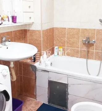Small equipped bathroom with a bathtub, washbasin, and washing machine. - image 4