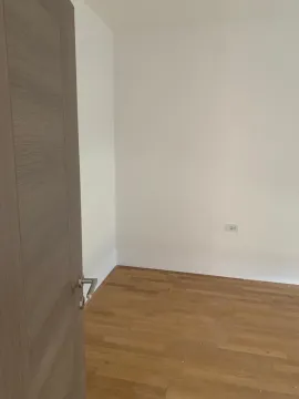 Prazna soba sa drvenim podom i bijelim zidovima viđena kroz poluotvorena vrata. - image 7