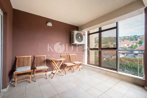 Natkriveni balkon sa drvenim stolom i stolicama i pogledom na naselje. - image 11