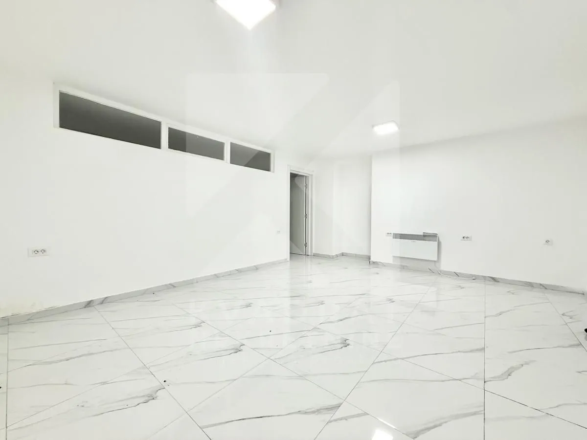 Empty bright room with white walls and marble tile flooring.