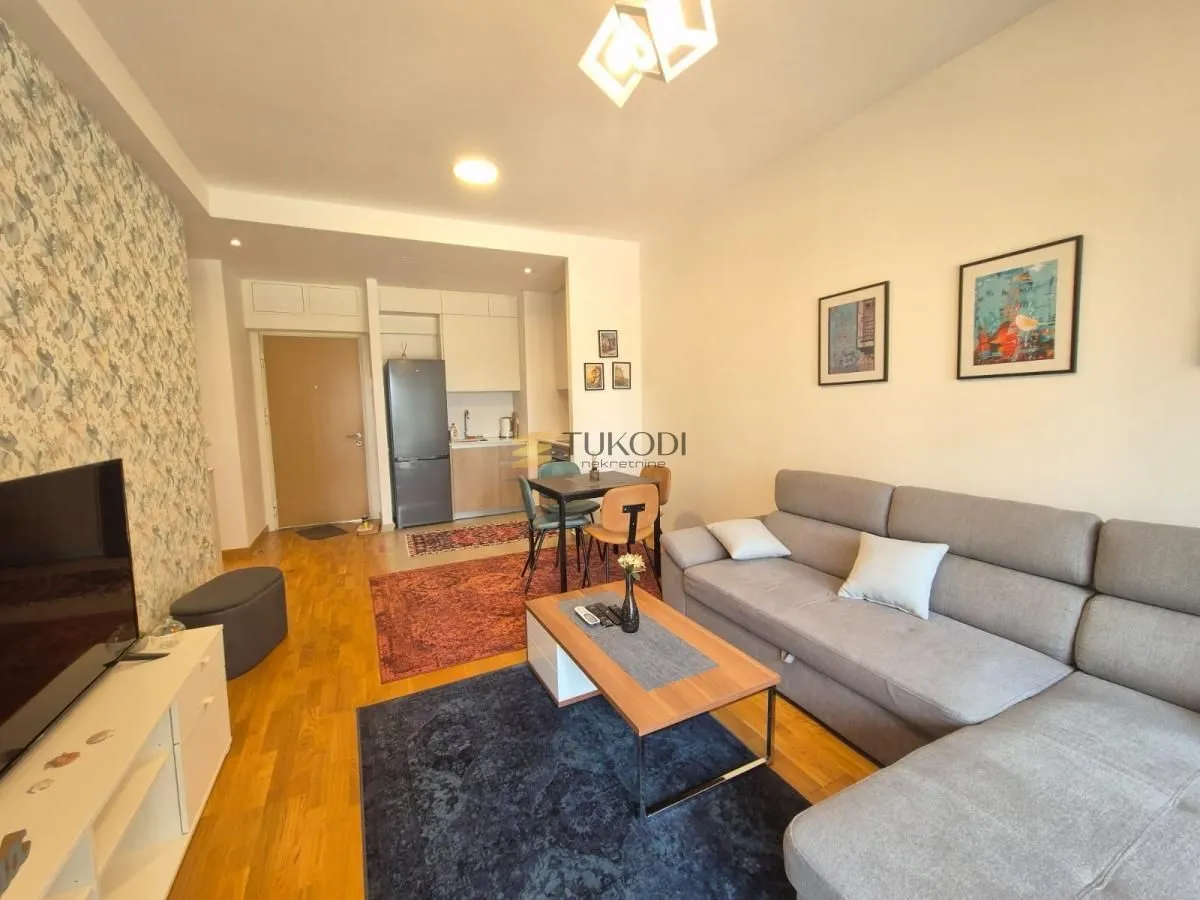 Living room with a sofa, coffee table, and a view towards the kitchen and dining area.