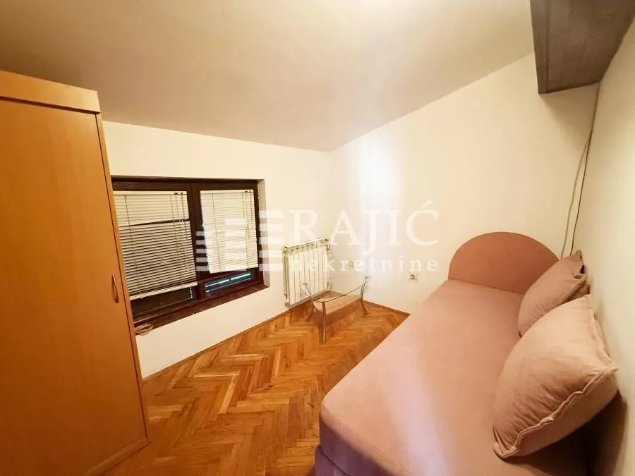 Furnished bedroom with a bed, wardrobe, and wooden flooring.