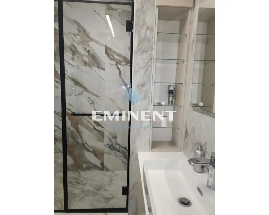 Modern bathroom with a marble-tiled shower cabin and washbasin.