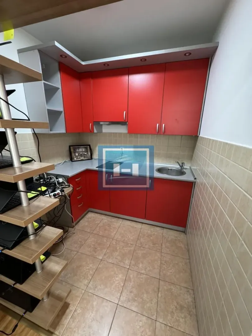 Small kitchen with red cabinets and tiled flooring.