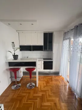 Moderna kuhinja sa bijelim elementima, šankom i crvenim barskim stolicama. - image 3