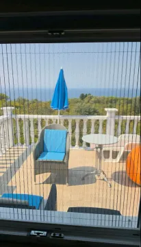View of the sea and greenery from the terrace through a protective net. - image 13