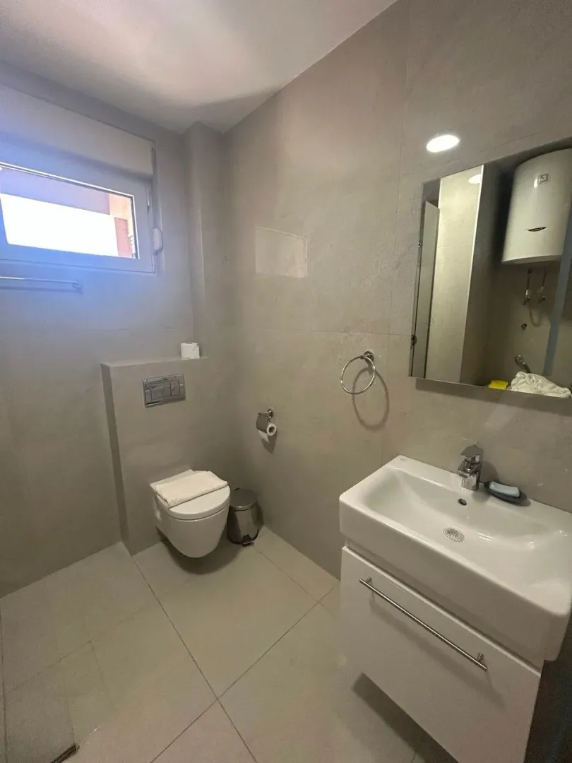 Moderne kupatilo sa umivaonikom, WC šoljom i prozorom.