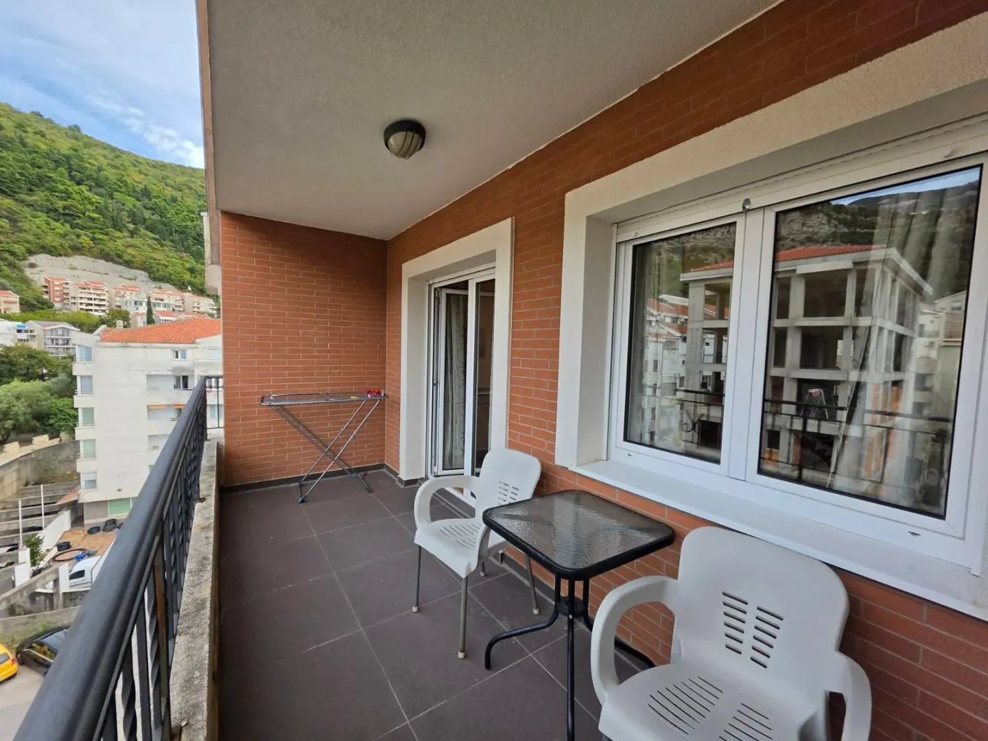 Natkriveni balkon sa garniturom za sjedenje i pogledom na okolinu.