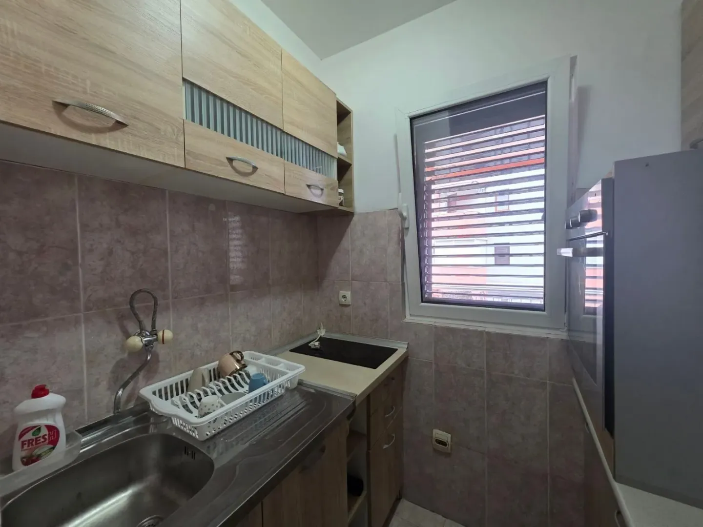 Small kitchen with a sink, cabinetry, and a window.