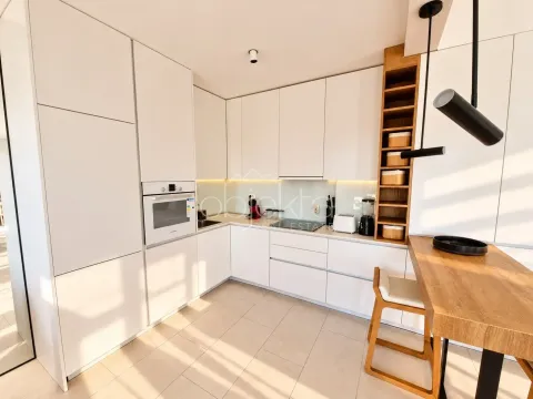 Modern white kitchen with a wooden bar and built-in appliances. - image 11