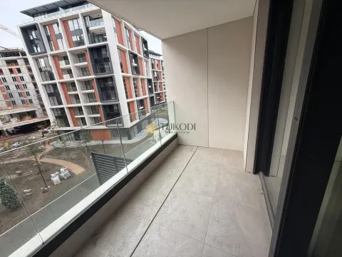 Nenamešten balkon sa staklenom ogradom i pogledom na naselje i gradilište. - image 9
