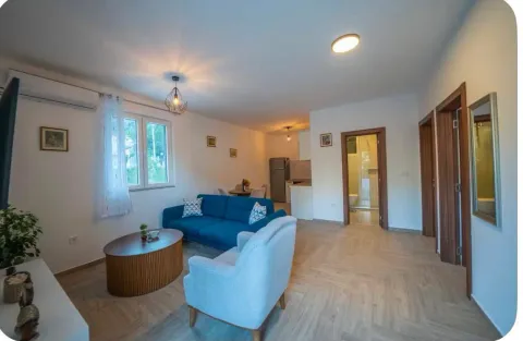 Spacious living room with a blue sofa, armchair, and a dining area in the background. - image 8