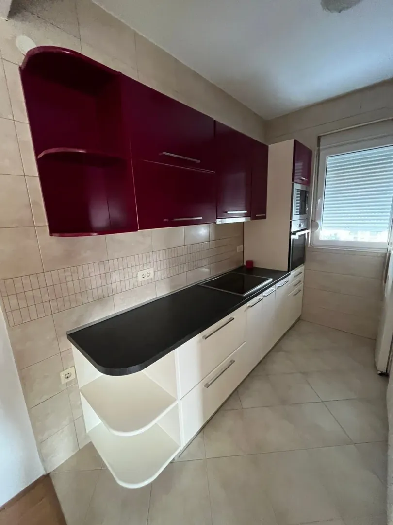 Smaller kitchen with white lower and dark red upper cabinets.