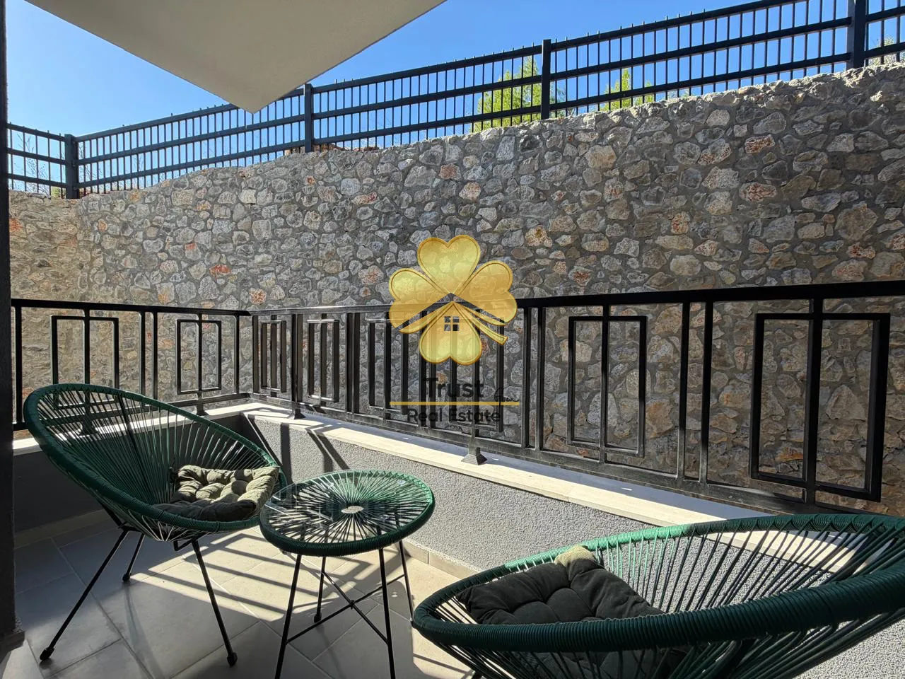 Small terrace with seating furniture and a stone wall in the background.