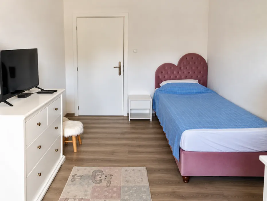 Bedroom with a bed, dresser, and television.
