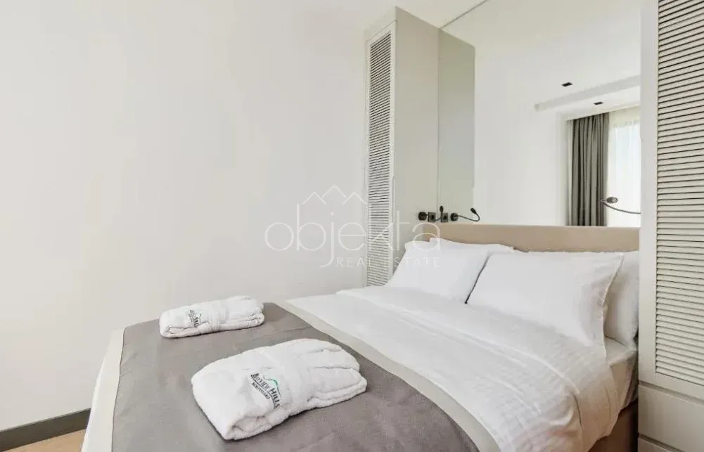 Modern bedroom with a double bed, white linens and a built-in wardrobe.