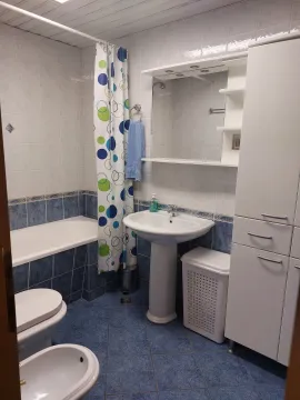 A functional bathroom featuring blue tiles, a bathtub, a sink, and white cabinets. - image 8