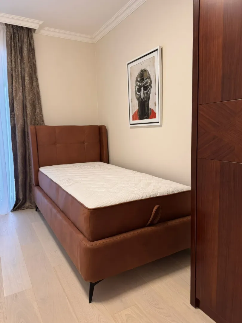 Small bedroom with a brown leather bed and a wardrobe.