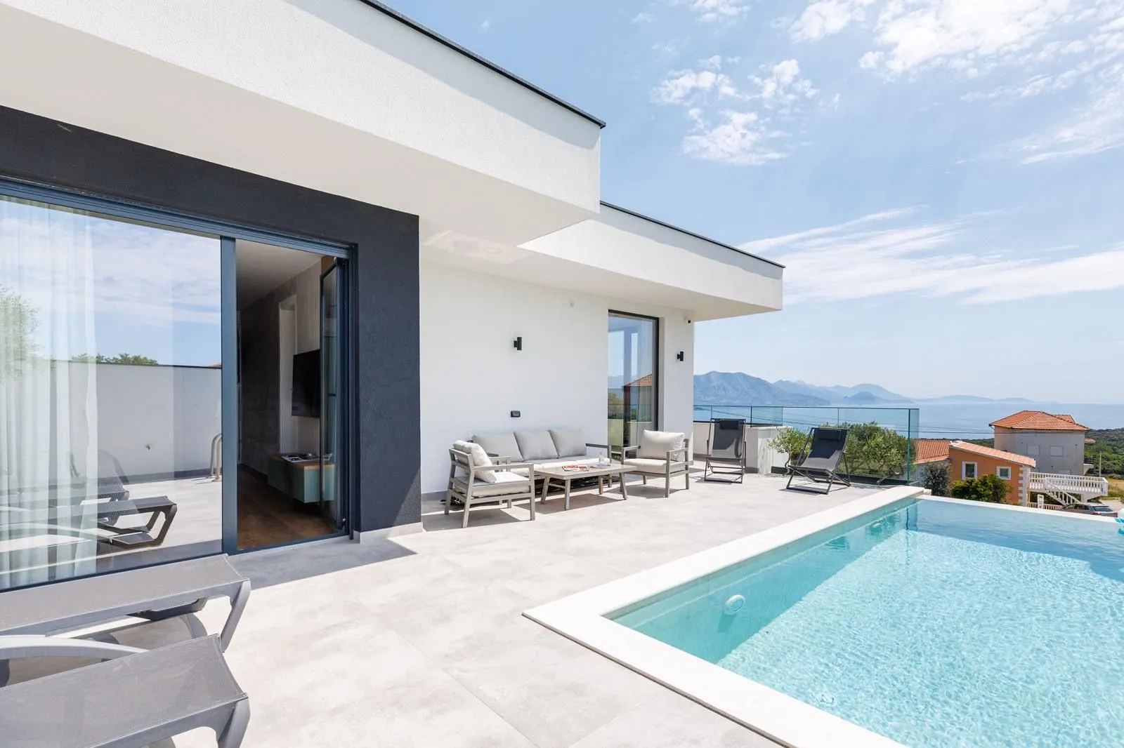 Modern terrace with a swimming pool and sea view in front of the villa.