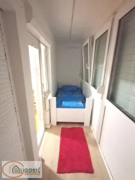Enclosed balcony with a bed and a red runner rug on the floor. - image 8