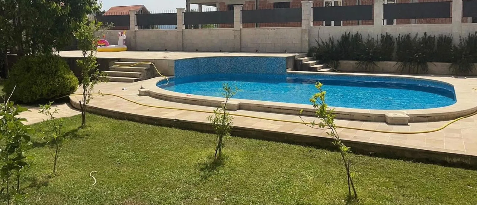 Yard with a swimming pool, lawn and paved patio area.