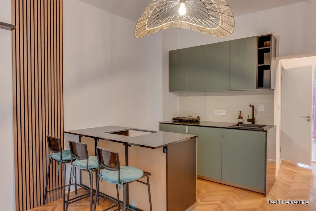 Modern kitchen with green cabinets and a breakfast bar with bar stools.