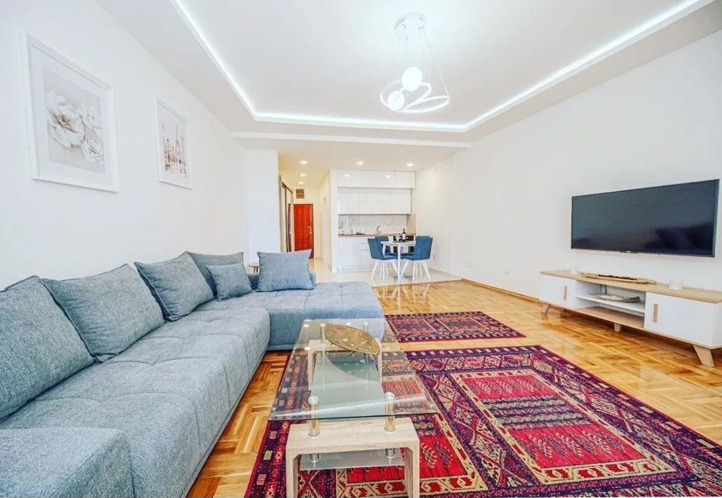 Spacious living room with a sofa, TV, and dining area in the background.
