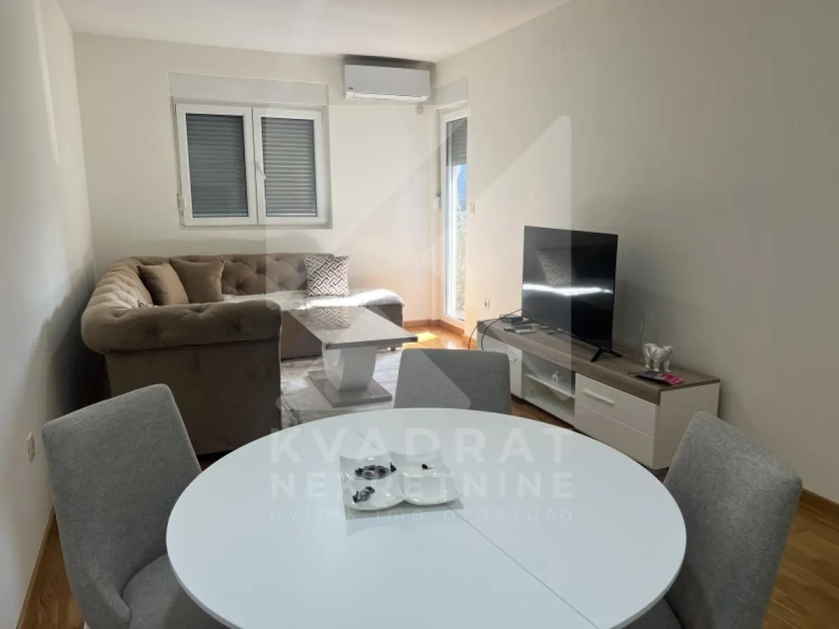 Living room with sofa, TV and dining table.