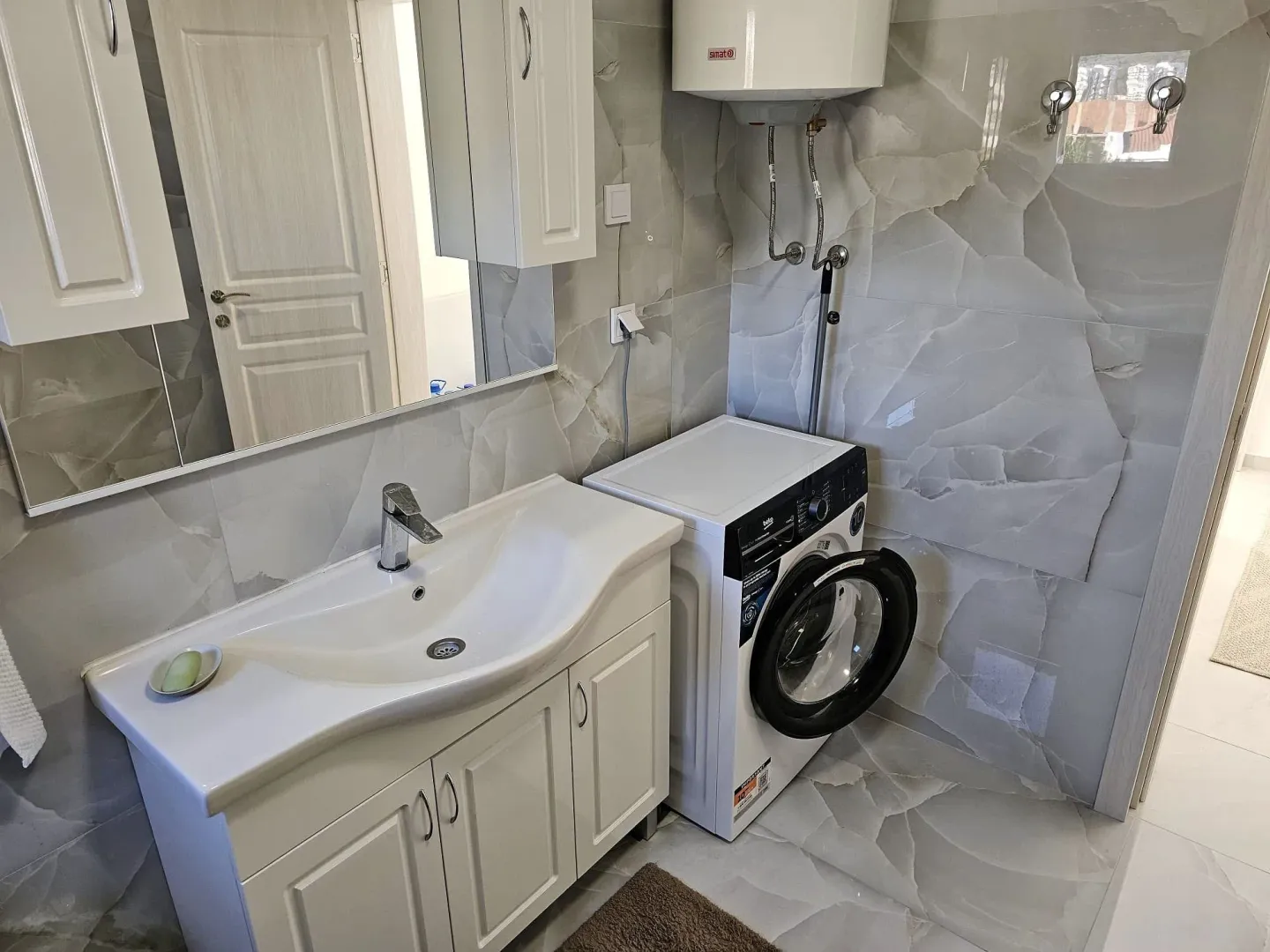 Bathroom with a vanity sink, washing machine, and wall-mounted water heater.