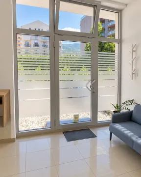 Entrance hallway with glass doors, seating furniture, and a bright floor. - image 3