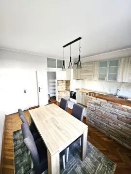 Dining area with a kitchen equipped with wooden elements and a table with chairs. - image 5