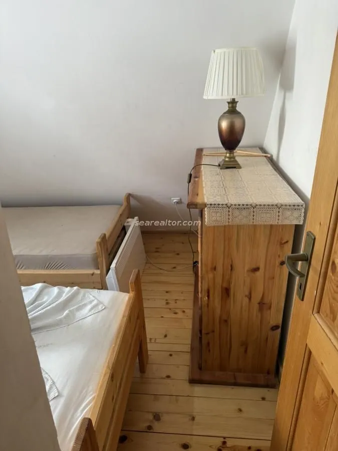 Manja spavaća soba sa drvenim krevetima i komodom.