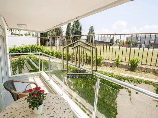 Covered balcony with a table, chairs, and a view of greenery.